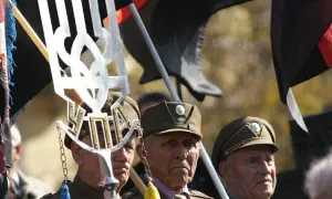 Weterani w mundurach, z symbolem Tryzub i flagami, w tym czarną z czerwonym pasem, przypominają o historii banderowców.