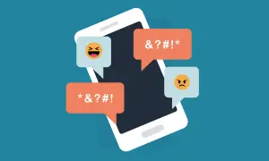 Telefon z dymkami pełnymi przekleństw i emotikon. Ilustracja do dyskusji o ustawie o mowie nienawiści i nowelizacji kodeksu karnego przez lewicę.