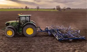 Zielony traktor z agregatem uprawowym na polu. Europejski zielony ład: dlaczego lewica popiera unijną politykę klimatyczną.