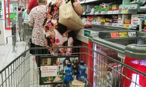 Kolejka w sklepie, ludzie robią zakupy. Widać ceny produktów, przypominając o zakazie handlu w niedziele i święta.