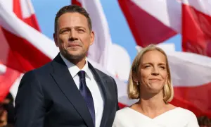 Rafał Trzaskowski z żoną Małgorzatą. W tle polskie flagi.