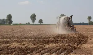 Traktor na polu nawozi ziemię. To obraz tego, co pis zrobił dla polskiej wsi przez 8 lat: nowoczesne rolnictwo i troska o glebę.