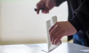 Ręka wrzuca kartę do głosowania do urny. To ważny moment, pokazujący, jak głosować.