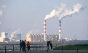 Dymiące kominy elektrowni. Polska 2050: transformacja węglowa koszty i terminy. Ludzie obserwują przemysł.