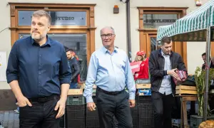 Mężczyźni w garniturach i koszulach, jeden z nich trzyma materiały wyborcze Lewicy.
