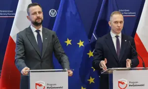 Dwóch mężczyzn w garniturach przemawia za mównicami. Tło stanowią flagi Polski i UE. Tematem dyskusji mogło być to, jak rządy PiS zmieniły strukturę polskiego wojska.