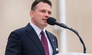 Sławomir Mentzen w garniturze przemawia do mikrofonu. Jego majątek budzi zainteresowanie.
