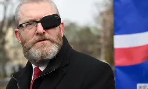 Grzegorz Braun w Sejmie, skandale i realne poparcie dla partii. Mężczyzna w okularach i opasce na oku, na tle flagi.