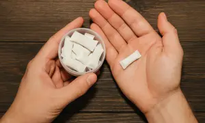 Dłonie trzymające pojemnik z białymi woreczkami nikotynowymi i jeden woreczek na dłoni. Czy snus jest legalny w Polsce?