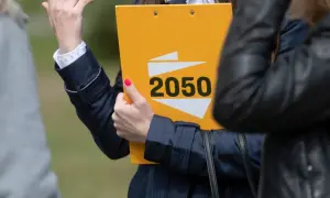 Kobieta prezentuje żółtą teczkę z napisem "2050", symbolizującą strategię polską 2050 na wybory samorządowe i europejskie.