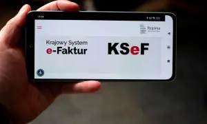 Dłoń trzyma smartfon z widocznym ekranem logowania do KSeF. Użytkownik napotyka problem z logowaniem do Krajowego Systemu e-Faktur.