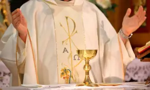 Ksiądz w białej szacie z symbolem Chi-Ro, kielich mszalny. Dyskusja o likwidacji funduszu kościelnego, renegocjacji konkordatu i postulatach lewicy.