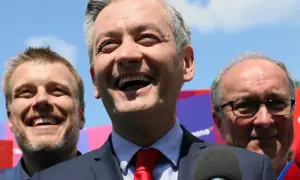 Uśmiechnięty polityk z czerwonym krawatem, w otoczeniu innych mężczyzn. Analiza struktury elektoratu partii, kogo reprezentuje lewica.