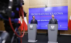 Dwóch mężczyzn w garniturach stoi za mównicami z godłem Polski, na tle ekranu z napisem "Prokuratura Krajowa".