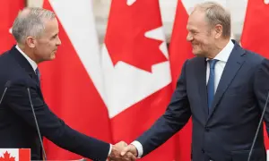 Dwóch polityków ściska sobie dłonie na tle flag Kanady. Wzmocnienie relacji polska-kanada.