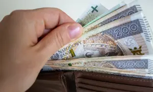 Dłoń wsuwa banknoty 200 zł do portfela. To symbol obietnic Koalicji Obywatelskiej dotyczących składki zdrowotnej dla przedsiębiorców.