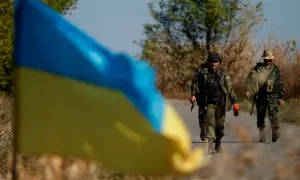 Ukraińska flaga na pierwszym planie, za nią dwaj żołnierze idący drogą. Hasło "stop ukrainizacji Polski" budziło kontrowersje, a Konfederacja używała go w swojej retoryce.