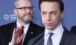 Dwóch mężczyzn w garniturach, jeden z brodą i okularami, drugi z wyrazem twarzy.