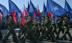 Żołnierze maszerują z flagami NATO i Polski. To obraz polityki obronnej koalicji obywatelskiej, która stawia na zakupy sprzętu wojskowego.