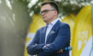 Mężczyzna w garniturze, z okularami, z mikrofonem w dłoni. Symboliczne przedstawienie debaty: Polska 2050 vs Nowa Lewica, główne osie sporu ideologicznego.