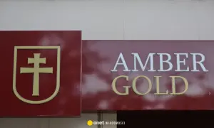 Złoty symbol krzyża na bordowym tle obok napisu AMBER GOLD.