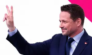 Rafał Trzaskowski pokazuje dwa palce, symbolizując zwycięstwo.