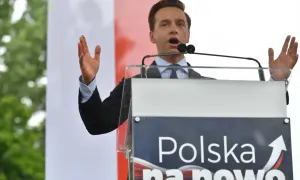 Mężczyzna przemawia przy mównicy z napisem "Polska na nowo". Konfederacja a podatki – chce znieść PIT, CIT i VAT, by uwolnić gospodarkę.