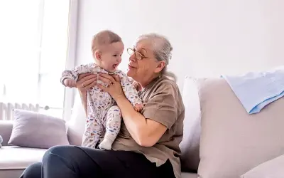 Babcia tuli niemowlę w piżamce z autkami. Czas spędzony w babciowych warunkach to czysta radość.