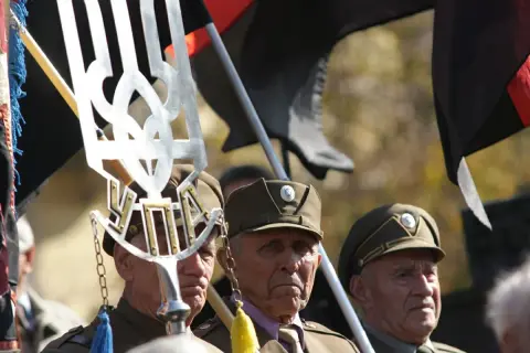 Weterani w mundurach, z symbolem Tryzub i flagami, w tym czarną z czerwonym pasem, przypominają o historii banderowców.