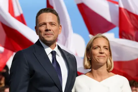 Rafał Trzaskowski z żoną Małgorzatą. W tle polskie flagi.