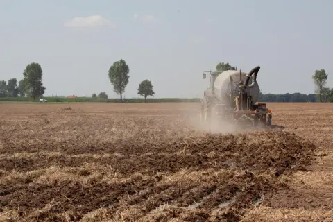 Traktor na polu nawozi ziemię. To obraz tego, co pis zrobił dla polskiej wsi przez 8 lat: nowoczesne rolnictwo i troska o glebę.