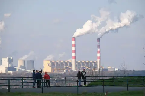 Dymiące kominy elektrowni. Polska 2050: transformacja węglowa koszty i terminy. Ludzie obserwują przemysł.