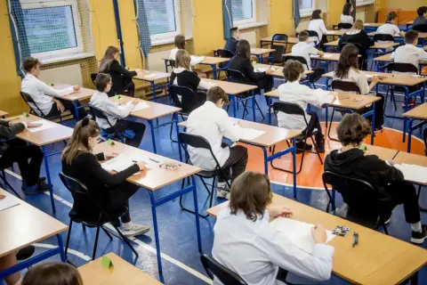 Uczniowie w skupieniu piszą egzaminy ósmoklasisty w sali gimnastycznej. Cisza i powaga towarzyszą temu ważnemu dniu.