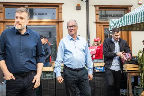 Mężczyźni w garniturach i koszulach, jeden z nich trzyma materiały wyborcze Lewicy.