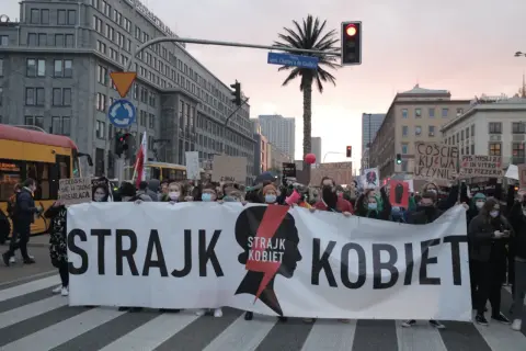 Protest Strajku Kobiet na ulicach Warszawy. Uczestnicy niosą transparent "STRAJK KOBIET". Jak protesty strajku kobiet wpłynęły na poparcie PiS?