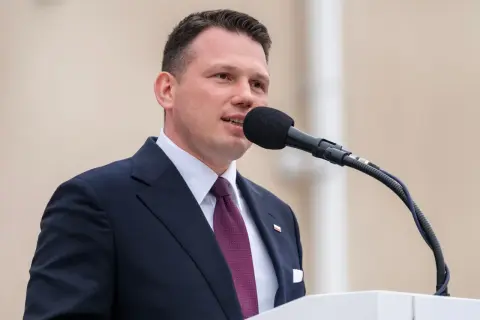 Sławomir Mentzen w garniturze przemawia do mikrofonu. Jego majątek budzi zainteresowanie.