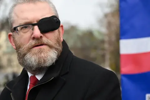 Grzegorz Braun w Sejmie, skandale i realne poparcie dla partii. Mężczyzna w okularach i opasce na oku, na tle flagi.