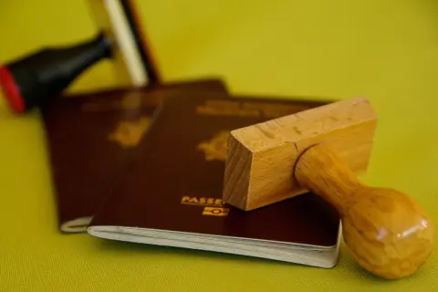 Pasporty i pieczątki, symbolizujące podróże, ale też potencjalną deportację.