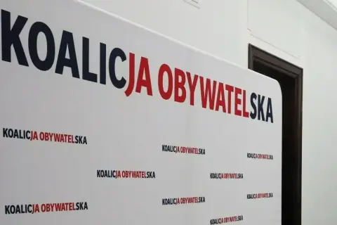Białe tło z napisem "KOALICJA OBYWATELSKA" w dużych, czerwono-granatowych literach. Pod spodem powtarza się mniejszy napis. To symboliczne tło dla dyskusji o stosunku Koalicji Obywatelskiej do Europejskiego Zielonego Ładu.