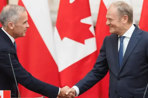 Dwóch polityków ściska sobie dłonie na tle flag Kanady. Wzmocnienie relacji polska-kanada.