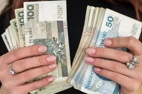 Dłonie z paznokciami pomalowanymi na jasny róż trzymają stosy polskich złotówek. W jednej ręce banknoty 100 zł, w drugiej 50 zł. To pewnie babciowe na drobne wydatki.