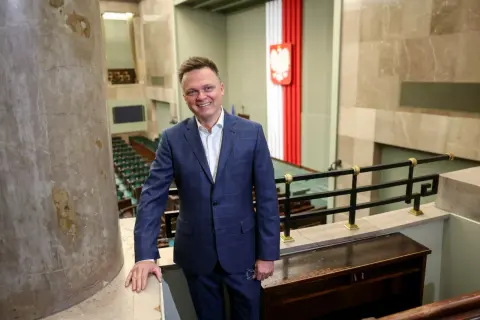Szymon Hołownia jako Marszałek Sejmu: ocena jego kadencji i potencjalne wpadki. Uśmiechnięty polityk w garniturze na tle sali sejmowej.