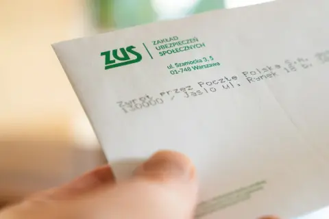 Dłoń trzyma dokument ZUS. Konfederacja i dobrowolny ZUS dla firm – dokładne kalkulacje są kluczowe dla przedsiębiorców.