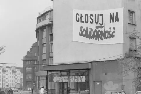 Transparent baner "Głosuj na Solidarność" na budynku, symboliczny protest przeciwko komunizmowi.