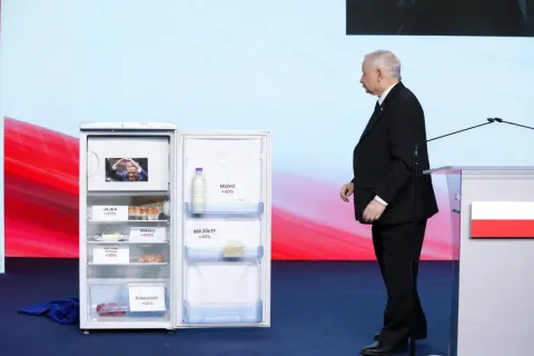 Otwarta lodówka z produktami i etykietami wzrostu cen, obok polityk. Ilustracja programu gospodarczego PiS a realia inflacji.