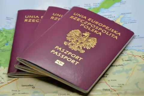 Trzy polskie paszporty leżą na mapie. Zastanawiasz się, ile się czeka na paszport?