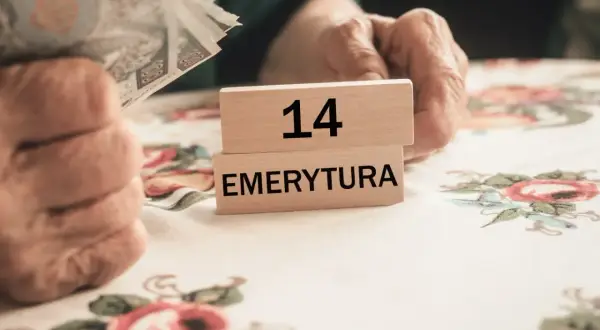 Dłonie trzymają pieniądze obok drewnianych klocków z napisem "14 EMERYTURA".