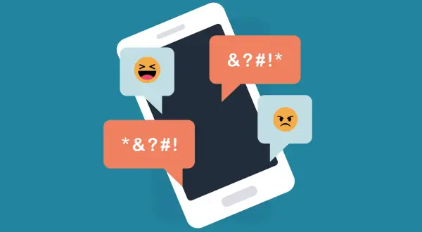 Telefon z dymkami pełnymi przekleństw i emotikon. Ilustracja do dyskusji o ustawie o mowie nienawiści i nowelizacji kodeksu karnego przez lewicę.