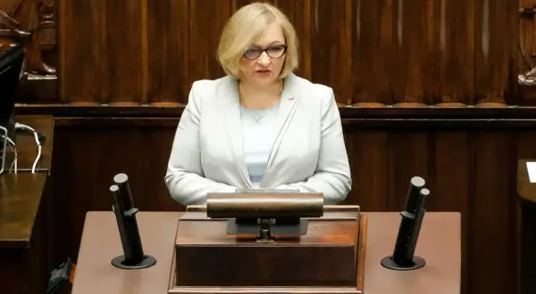 Kobieta w jasnej marynarce przemawia w sejmie, dyskutując o wpływie polityki PiS na prawa kobiet w Polsce.