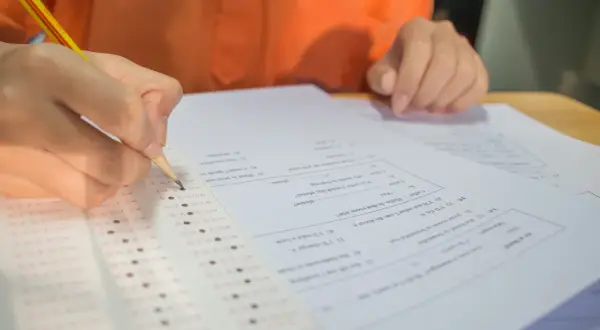 Ręka z ołówkiem zaznacza odpowiedzi na arkuszu testowym. Zastanawiasz się, ile punktów na maturze z matematyki zdobędziesz?